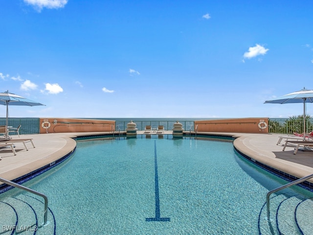 view of swimming pool with a patio and a water view