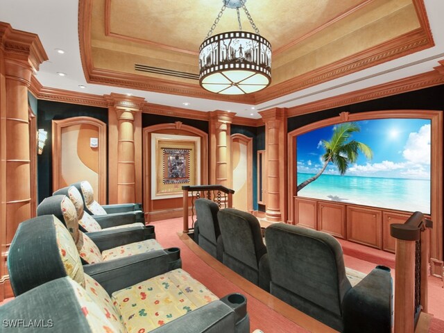 cinema room with ornamental molding, a tray ceiling, decorative columns, light carpet, and a notable chandelier