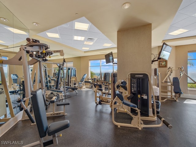 exercise room with a drop ceiling and a healthy amount of sunlight