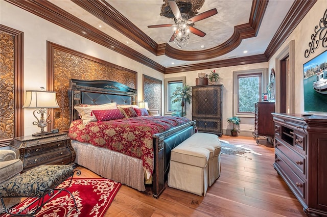 bedroom featuring ceiling fan, hardwood / wood-style flooring, a tray ceiling, and crown molding