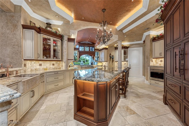 kitchen with crown molding, oven, decorative light fixtures, cream cabinets, and a notable chandelier