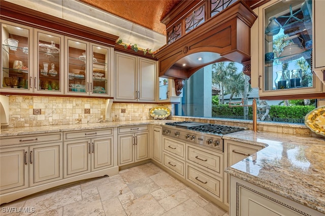 kitchen featuring cream cabinetry, backsplash, stainless steel gas cooktop, and light stone countertops