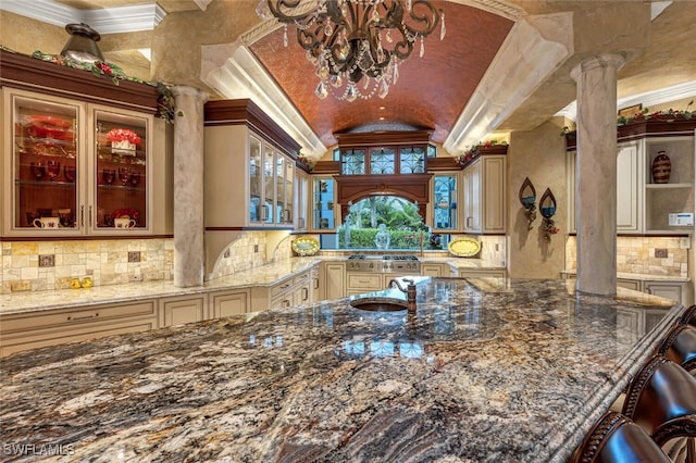 kitchen featuring dark stone countertops, crown molding, and ornate columns