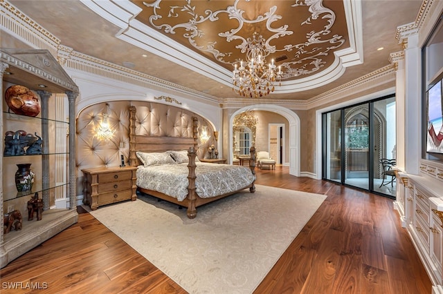 bedroom with crown molding, wood-type flooring, a tray ceiling, and access to outside