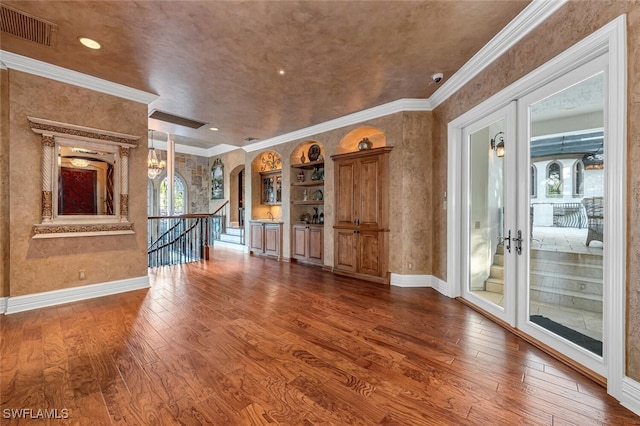 unfurnished living room with wood-type flooring, crown molding, and french doors