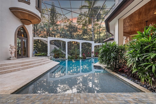 pool at dusk with a patio and french doors