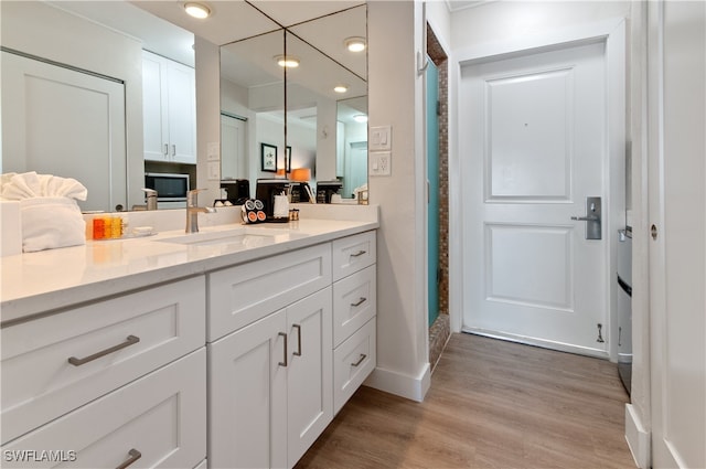 bathroom featuring a shower, baseboards, wood finished floors, and vanity