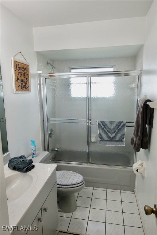 full bathroom featuring tile patterned flooring, vanity, toilet, and bath / shower combo with glass door