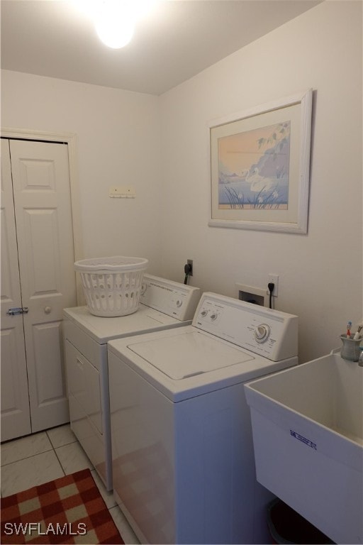 laundry room with light tile patterned floors, sink, and washing machine and clothes dryer