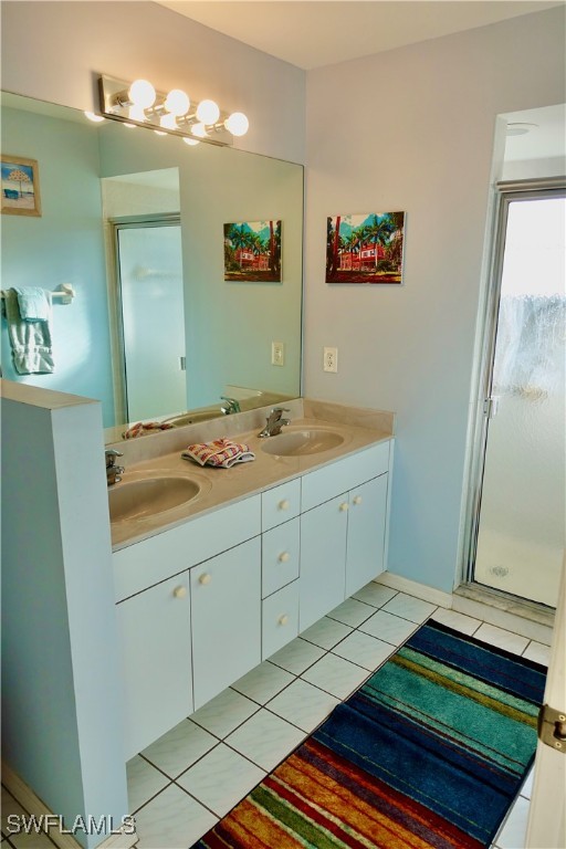 bathroom with tile patterned flooring, a shower with door, and vanity