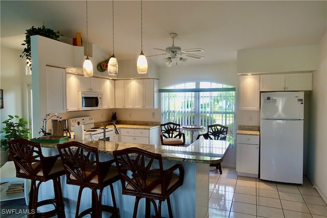 kitchen featuring white cabinets, light tile patterned flooring, kitchen peninsula, white appliances, and a breakfast bar