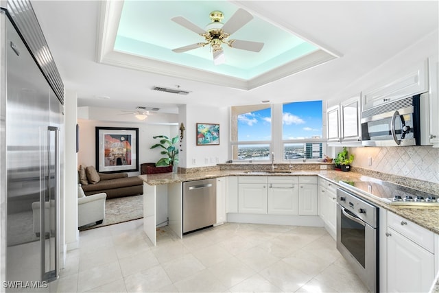 kitchen featuring kitchen peninsula, tasteful backsplash, appliances with stainless steel finishes, white cabinetry, and sink