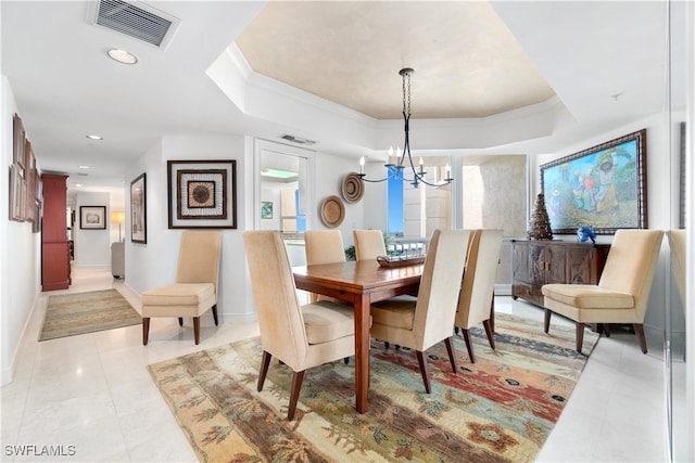 dining space with ornamental molding, a notable chandelier, and a raised ceiling