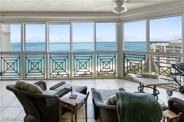 tiled living area with a textured ceiling, ceiling fan, and a water view