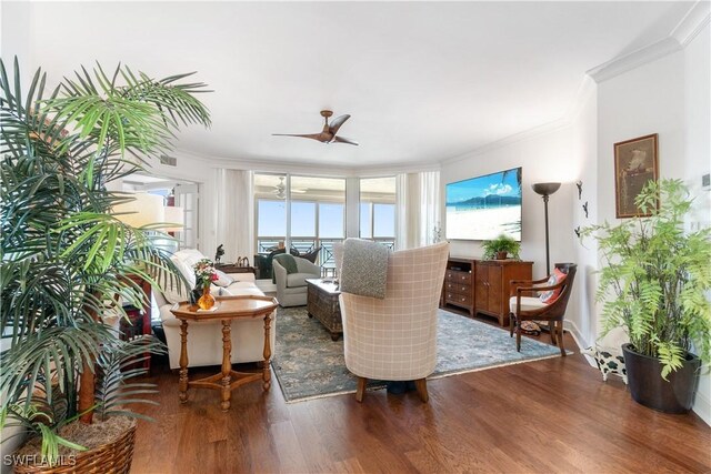 living area featuring wood finished floors, crown molding, and a ceiling fan