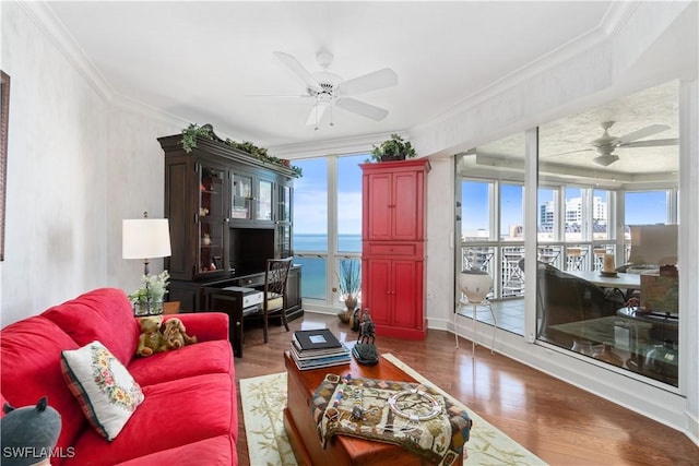 living room featuring wood finished floors, ceiling fan, ornamental molding, and a water view