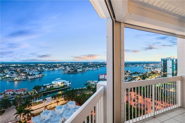 balcony at dusk featuring a water view