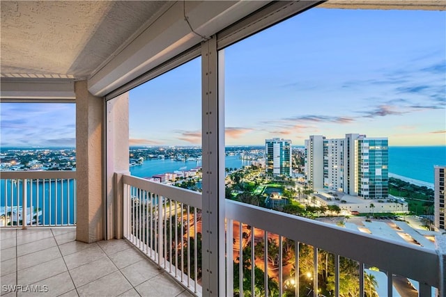 balcony at dusk with a view of city and a water view