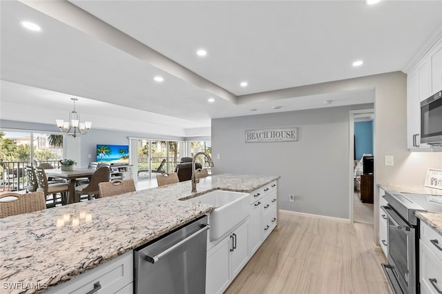 kitchen with a wealth of natural light, stainless steel appliances, sink, and white cabinetry