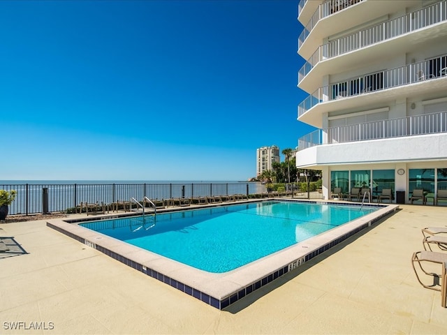 view of pool featuring a patio and a water view