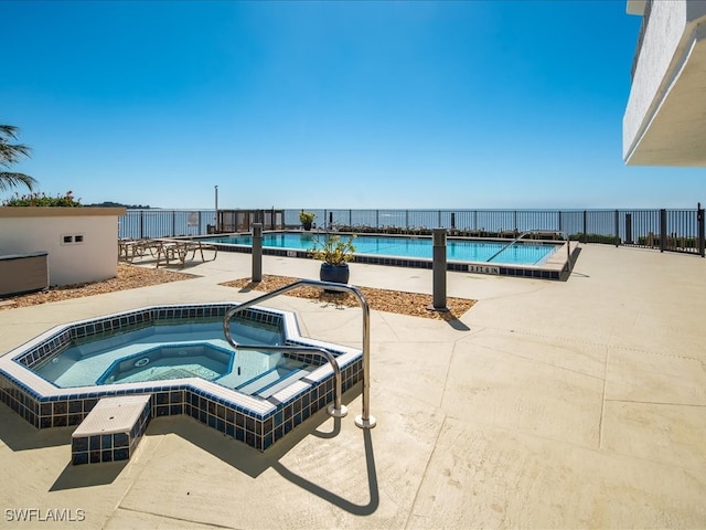 view of pool featuring a patio, a water view, and a community hot tub