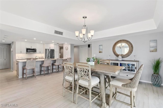 1036 S Collier Blvd Unit 101, Marco Island, FL 34145 - dining area featuring a chandelier, light wood finished floors, recessed lighting, baseboards, and a tray ceiling