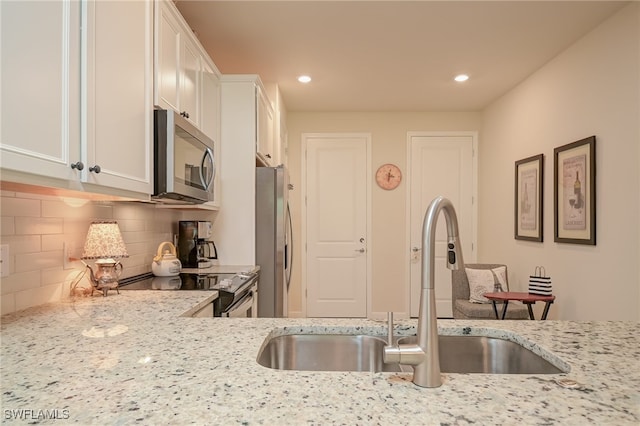 kitchen featuring light stone countertops, stainless steel appliances, sink, and white cabinetry