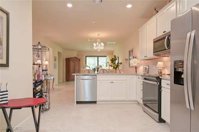 kitchen with appliances with stainless steel finishes, hanging light fixtures, white cabinets, backsplash, and a chandelier