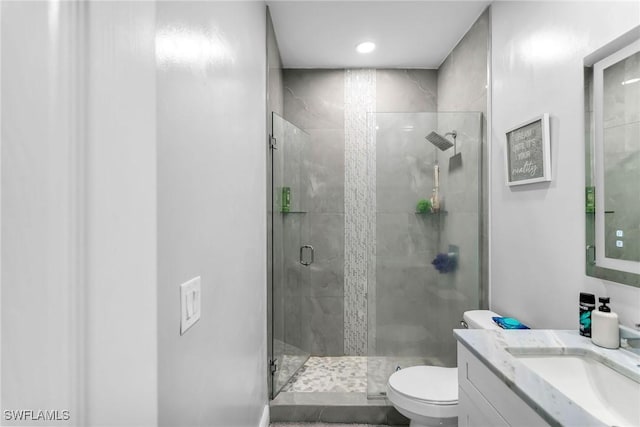 bathroom with toilet, a shower with door, and vanity