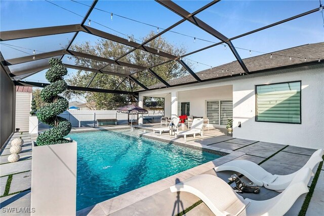 view of swimming pool featuring glass enclosure and a patio