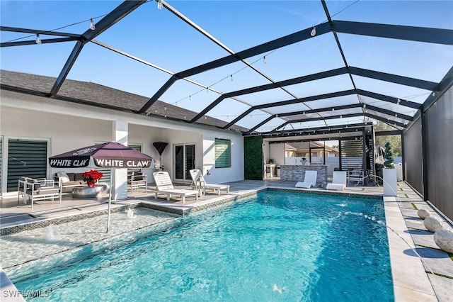 view of pool with pool water feature, glass enclosure, area for grilling, and a patio