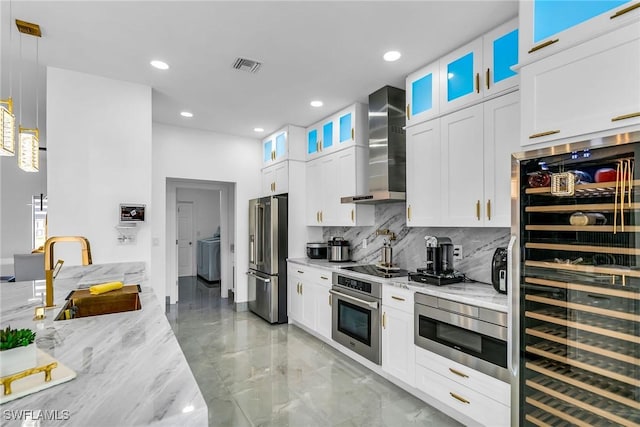 kitchen featuring white cabinetry, stainless steel appliances, beverage cooler, wall chimney exhaust hood, and sink