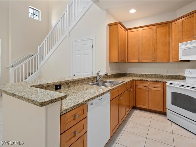 kitchen featuring white appliances, kitchen peninsula, light stone countertops, light tile patterned floors, and sink