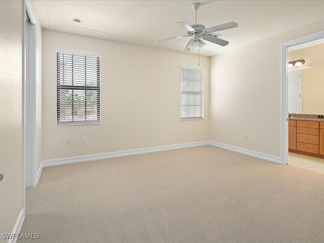 unfurnished bedroom with ceiling fan, light colored carpet, and ensuite bath