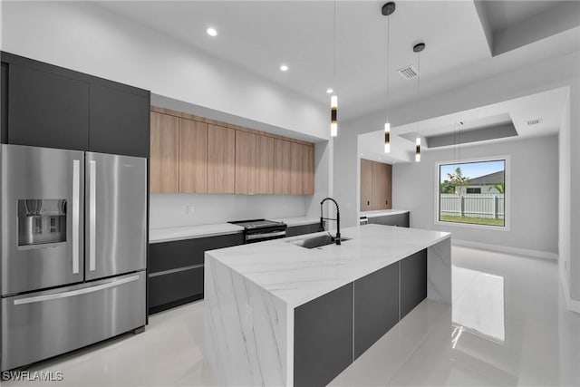 kitchen featuring sink, decorative light fixtures, stainless steel fridge with ice dispenser, light stone countertops, and a kitchen island with sink