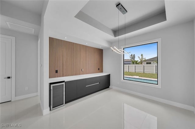 unfurnished dining area with baseboards and a raised ceiling