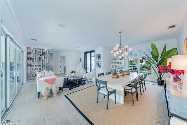 dining area featuring a chandelier, french doors, visible vents, and light wood-style flooring