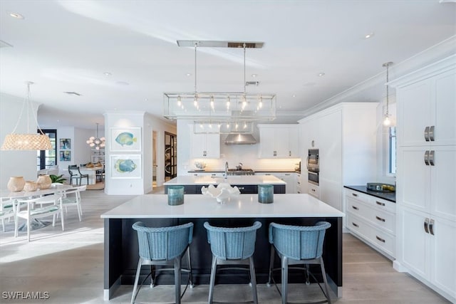 kitchen with a spacious island, tasteful backsplash, light countertops, hanging light fixtures, and white cabinets