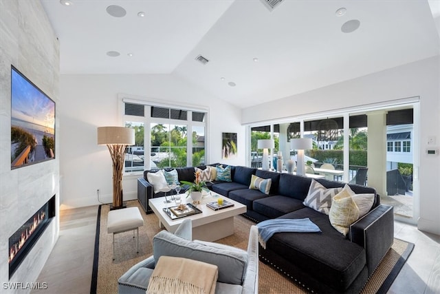 living area featuring visible vents, vaulted ceiling, a tiled fireplace, and recessed lighting