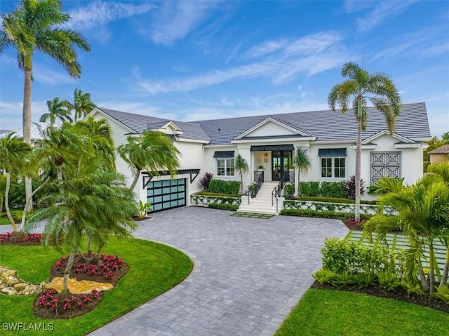 view of front of home with decorative driveway, french doors, stucco siding, a garage, and a front lawn