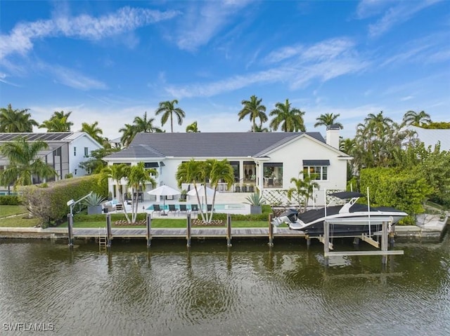 rear view of house with a water view, boat lift, and an outdoor pool