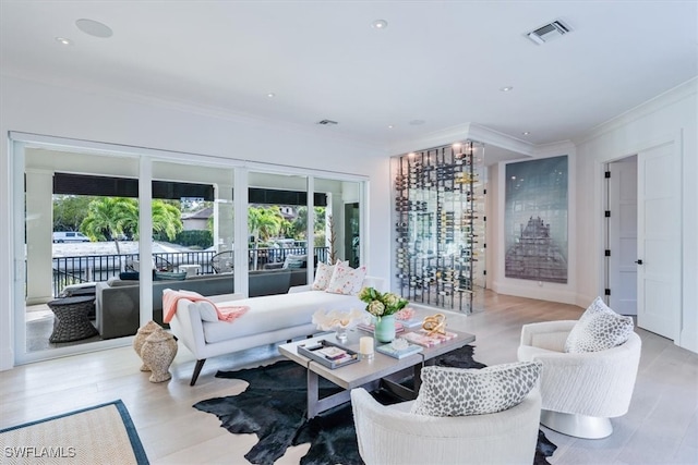 living room featuring light wood-style floors, visible vents, and crown molding