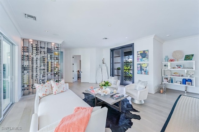 living room featuring light wood finished floors, ornamental molding, visible vents, and recessed lighting