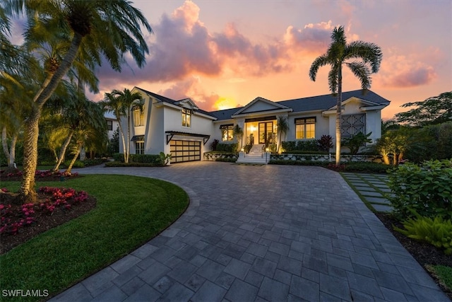 view of front facade featuring a garage, decorative driveway, a front yard, and stucco siding