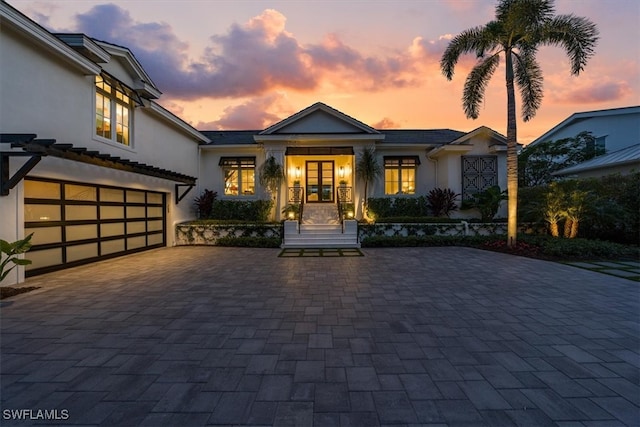 view of front of house featuring decorative driveway, an attached garage, and stucco siding