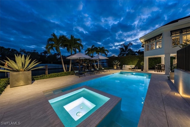 pool with a patio, fence, and an in ground hot tub