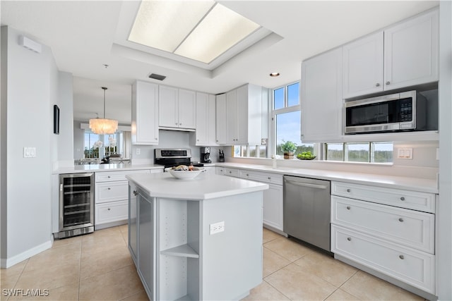 kitchen with stainless steel appliances, wine cooler, hanging light fixtures, a kitchen island, and white cabinets