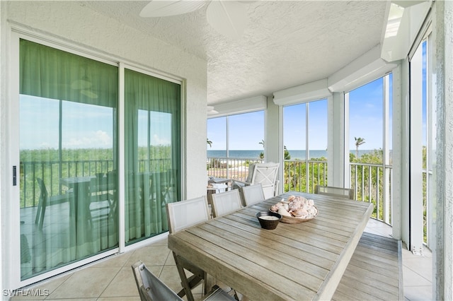 sunroom / solarium featuring ceiling fan, a wealth of natural light, and a water view