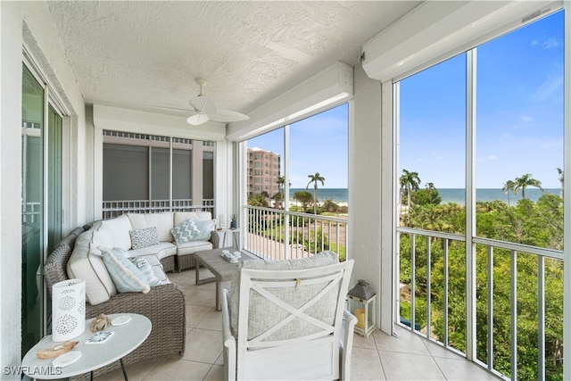 sunroom / solarium featuring ceiling fan and a water view