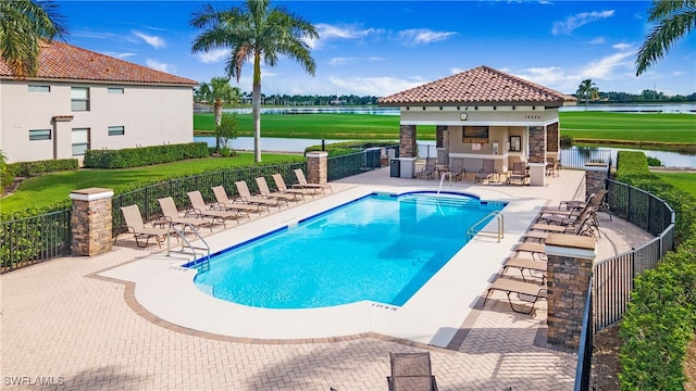 view of pool with area for grilling, a water view, and a patio